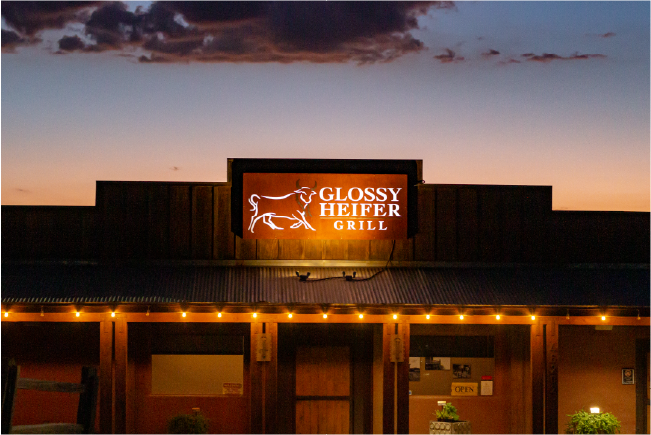 Glossy Heifer Grill exterior in New River Arizona at dusk with glowing signage, restaurant branding photography by Matthew Spaulding