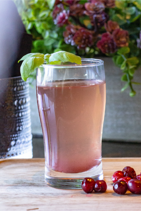 Pink mimosa cocktail with basil garnish and cranberries—Greek brunch beverage photography